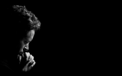 Light on man's face as he pray, dark background